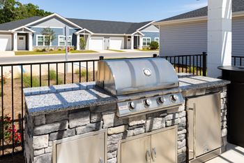 a stainless steel barbecue with a granite countertop in a backyard